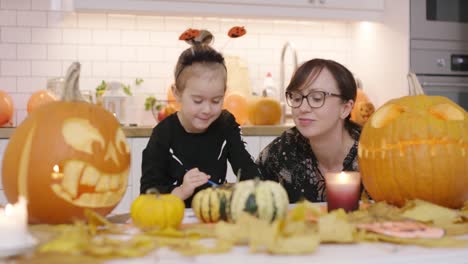 Mother-looking-at-daughter-painting-pumpkin