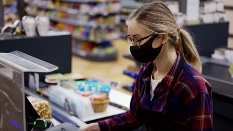 female cashier in a protective mask talking to a customer