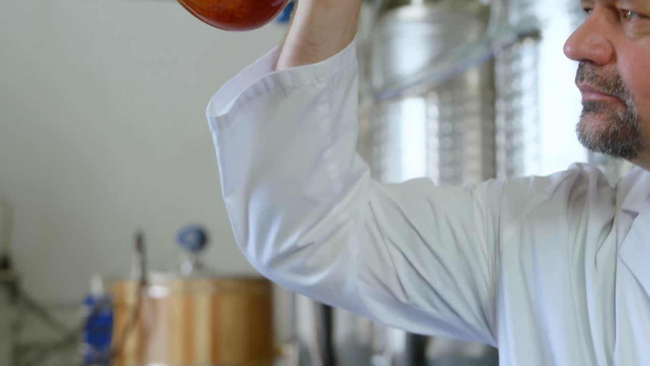 Male worker examining liquor in flask 4k