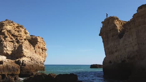 Ancho,-Pescador-Solitario-Lanza-Línea-Desde-La-Percha-En-Lo-Alto-Del-Acantilado-Del-Algarve,-Portugal