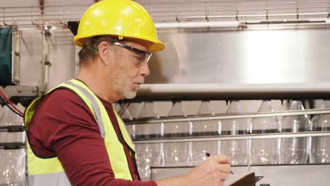 worker checking bottles on production line