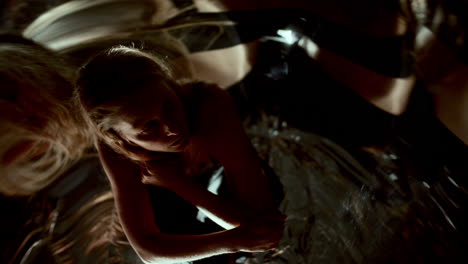 woman sitting curled up, surrounded by fluid mirrored distortions