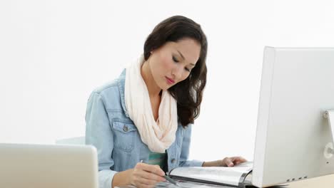 Asian-woman-working-at-desk-writing-in-folder