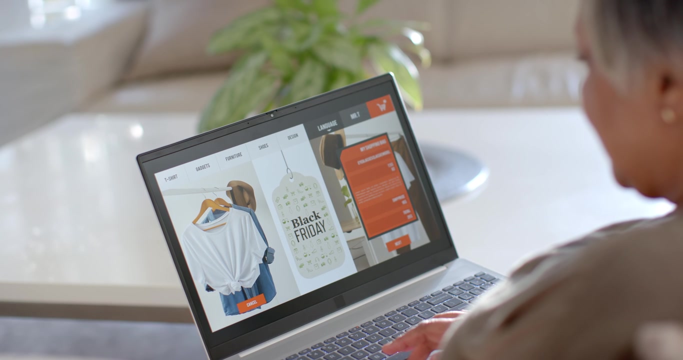 Una donna africana naviga sul laptop a casa, vede un'etichetta Black Friday, scorre un menu arancione, con spazio per il testo.