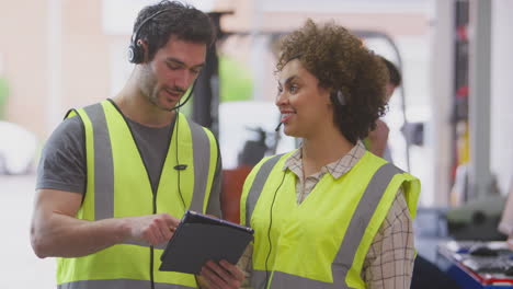 Trabajadores-Masculinos-Y-Femeninos-Que-Usan-Auriculares-En-Un-Almacén-De-Distribución-Logística-Usando-Una-Tableta-Digital