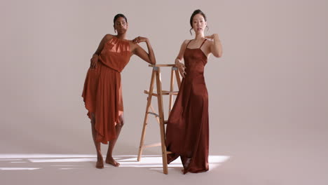 diverse female models entering studio leaning tilting on stepladder under soft light for shoot