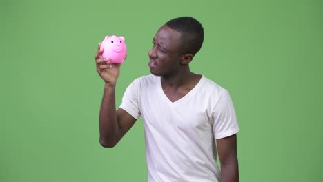 young african man holding piggy bank