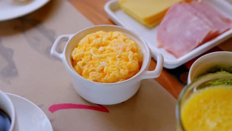 huevos revueltos recién preparados en una olla de cerámica blanca