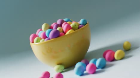 bowl with colorful easter eggs on green background with copy space