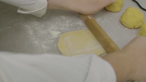 Chef-rolls-out-pasta-dough-on-kitchen-cooking-table