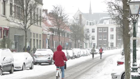 Menschen-Laufen-Und-Radeln-Während-Der-Pandemie-Auf-Einer-Verschneiten-Straße-In-Leiden,-Niederlande