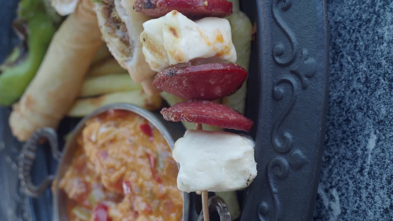 Close-up of a food platter with cheese and sausage skewers and other fried items