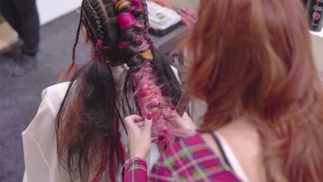 peluquería de jengibre está brading y arreglando trenzas de colores a cámara lenta