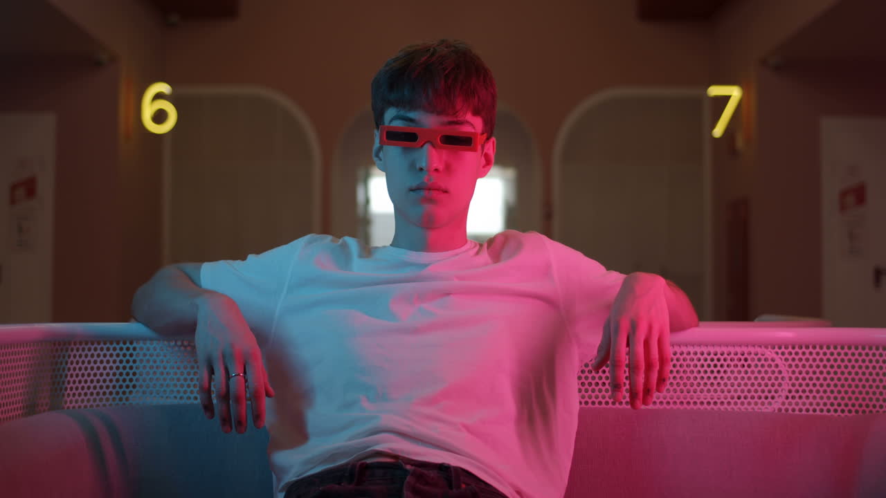 Man with red glasses in a neon lit room