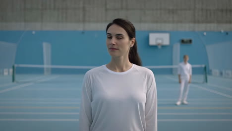 woman and another person on a blue indoor sports court