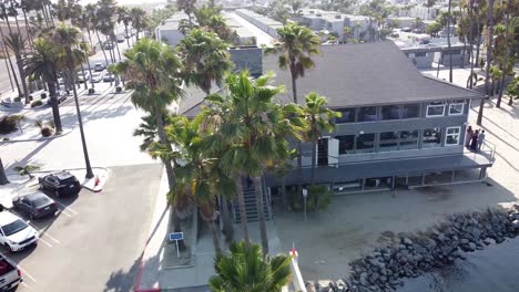 aerial view of a large building and people at the seaside - drone footage