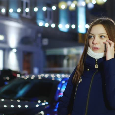 mujer joven camina por la ciudad de noche hablando por teléfono 1