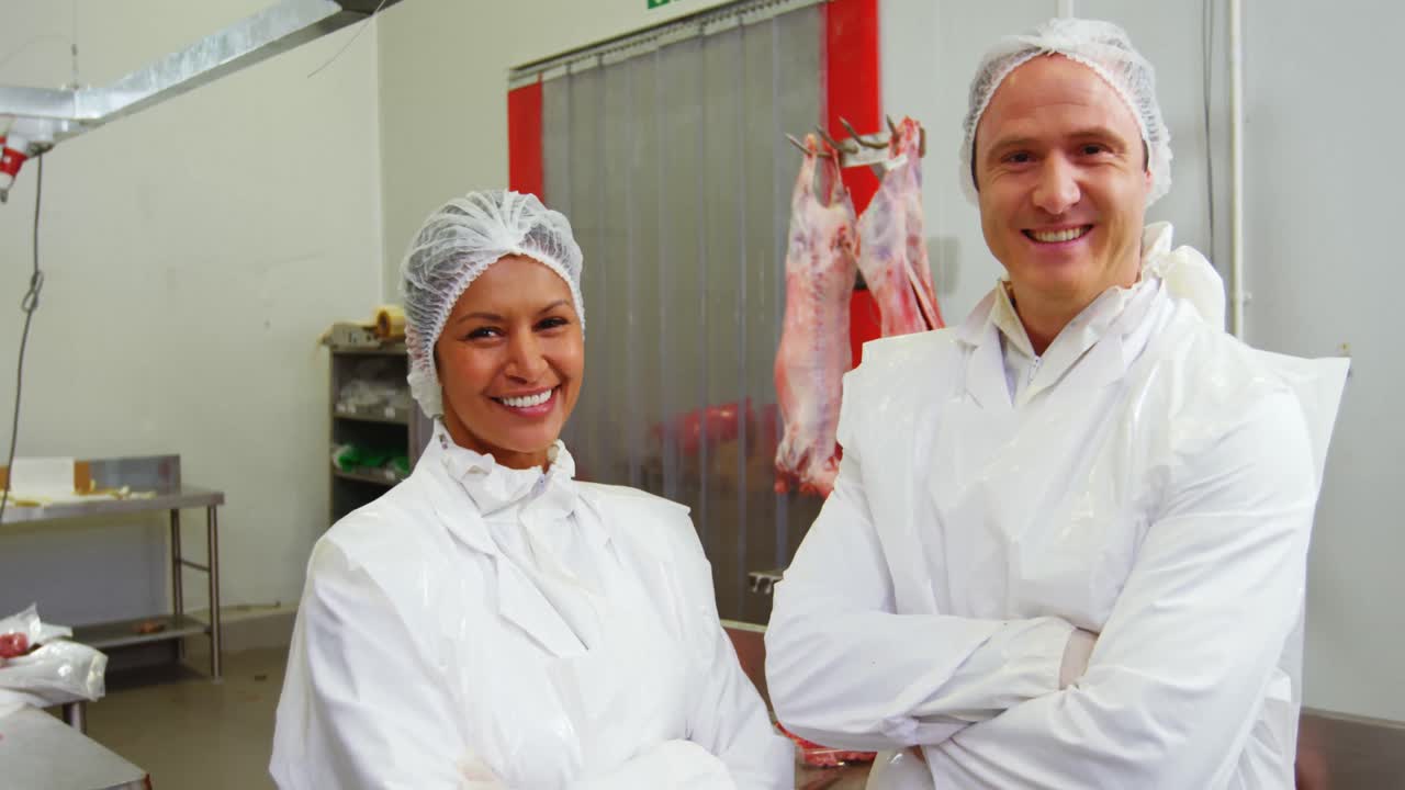 equipo de carnicero sonriente de pie con los brazos cruzados