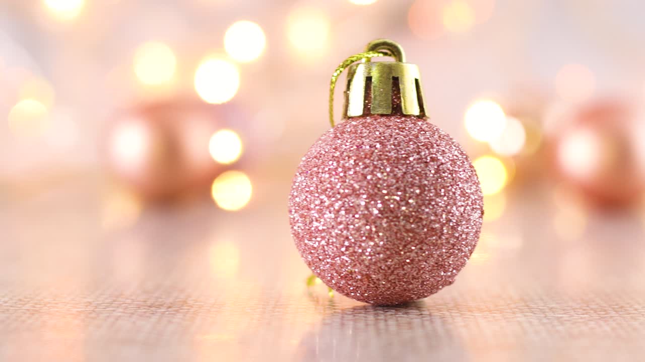 Pastelrosa glimmer julepynt på bordet med blinkende lys.