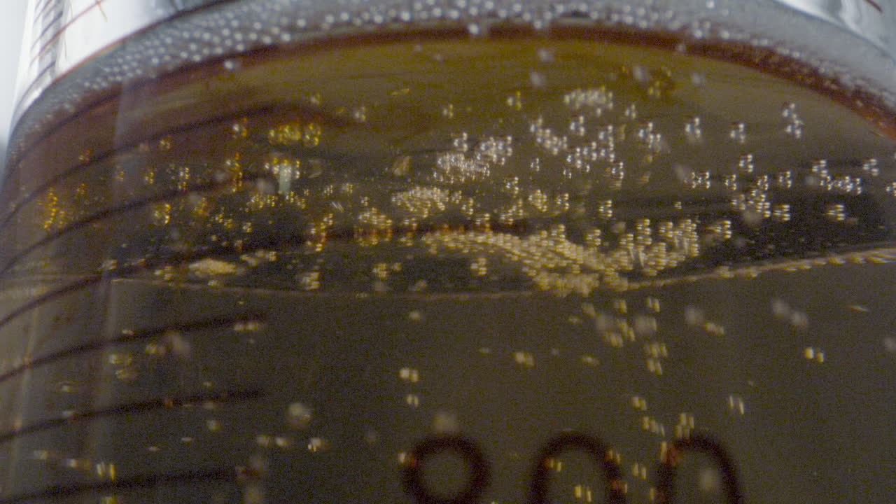Close-up of a drop of colored liquid descending from a burette and falling into a flask with gaseous liquid in a laboratory setting.