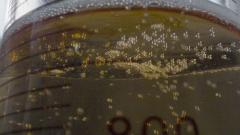 close-up of a drop of colored liquid descending from a burette and falling into a flask with gaseous liquid in a laboratory setting.