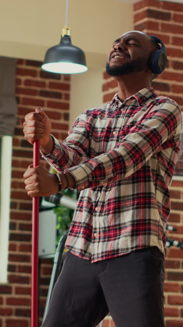 Vídeo vertical: pessoa moderna dançando e usando um esfregão para limpar o chão