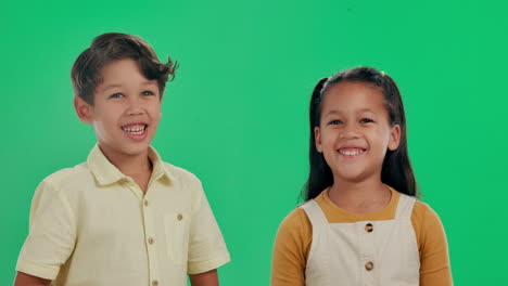 two smiling children on a green screen