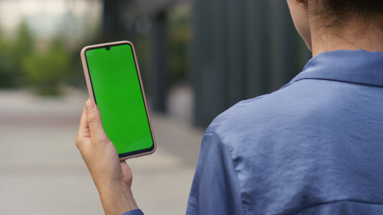 mano sosteniendo una maqueta de teléfono inteligente en la calle de primer plano. mujer de negocios caminando por la ciudad