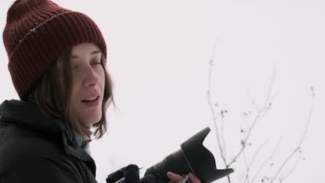 a young female photographer with camera smiles in snowy forest, fixed medium