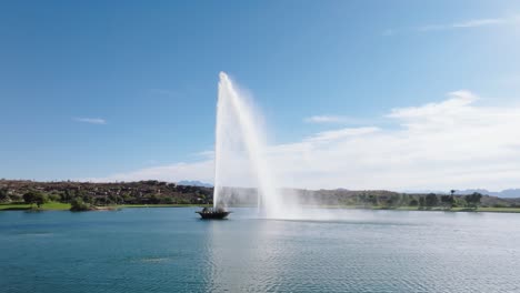 Aerial-dolly-to-center-fountain-of-water-flowing-and-reflecting-in-ripples-of-artificial-lake-in-Arizona