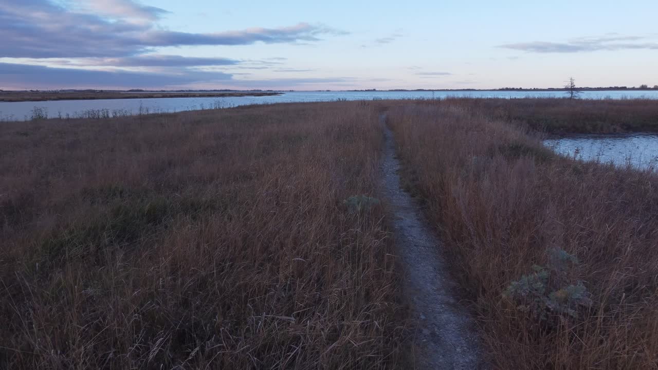 Hiking trail to lake in tall grass aerial winter evening