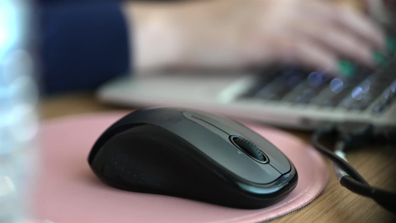 Female hand operating modern wireless mouse device and laptop