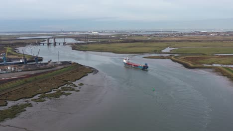 Amplia-Toma-Aérea-De-Seguimiento-De-Un-Barco-Que-Exporta-Mercancías,-Navegando-A-Lo-Largo-Del-Estuario-Del-Pantano