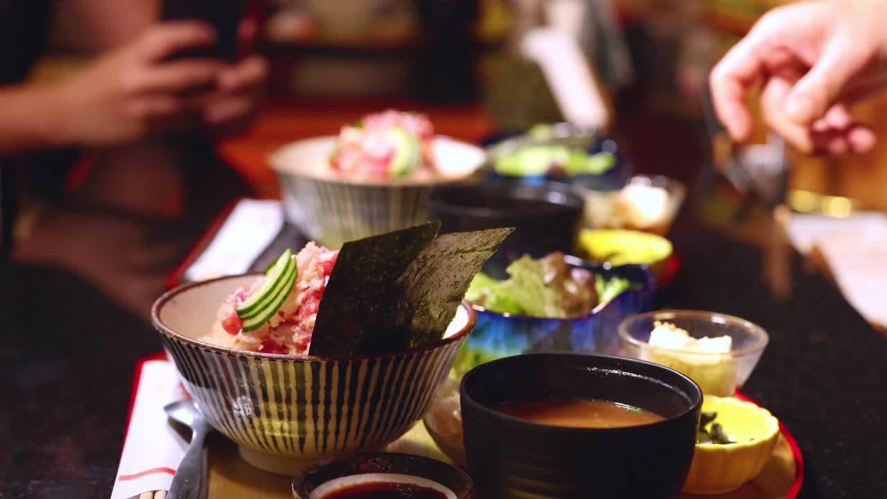 Uno chef giapponese in uniforme nera serve una ciotola tradizionale di chirashi e zuppa di miso