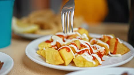 primer plano del plato típico español "patatas bravas", patatas asadas con ketchup y mayonesa sobre ellas