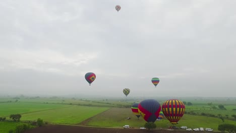 aerial view of hot air balloons floating over fields.