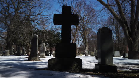 tombstones resting in a winter graveyard, wide shot panning right