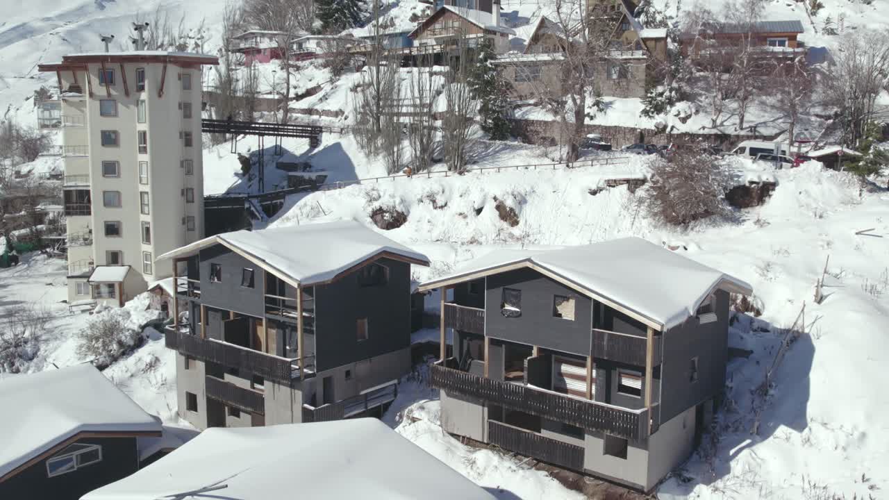 vista aérea de cerca de las cabañas en construcción en el pueblo montañoso nevado de farellones, construcción de madera y piedra de la zona, chile