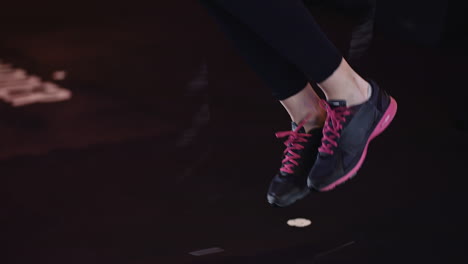 sección baja de mujer deportiva usando cuerda de saltar haciendo entrenamiento físico en el gimnasio