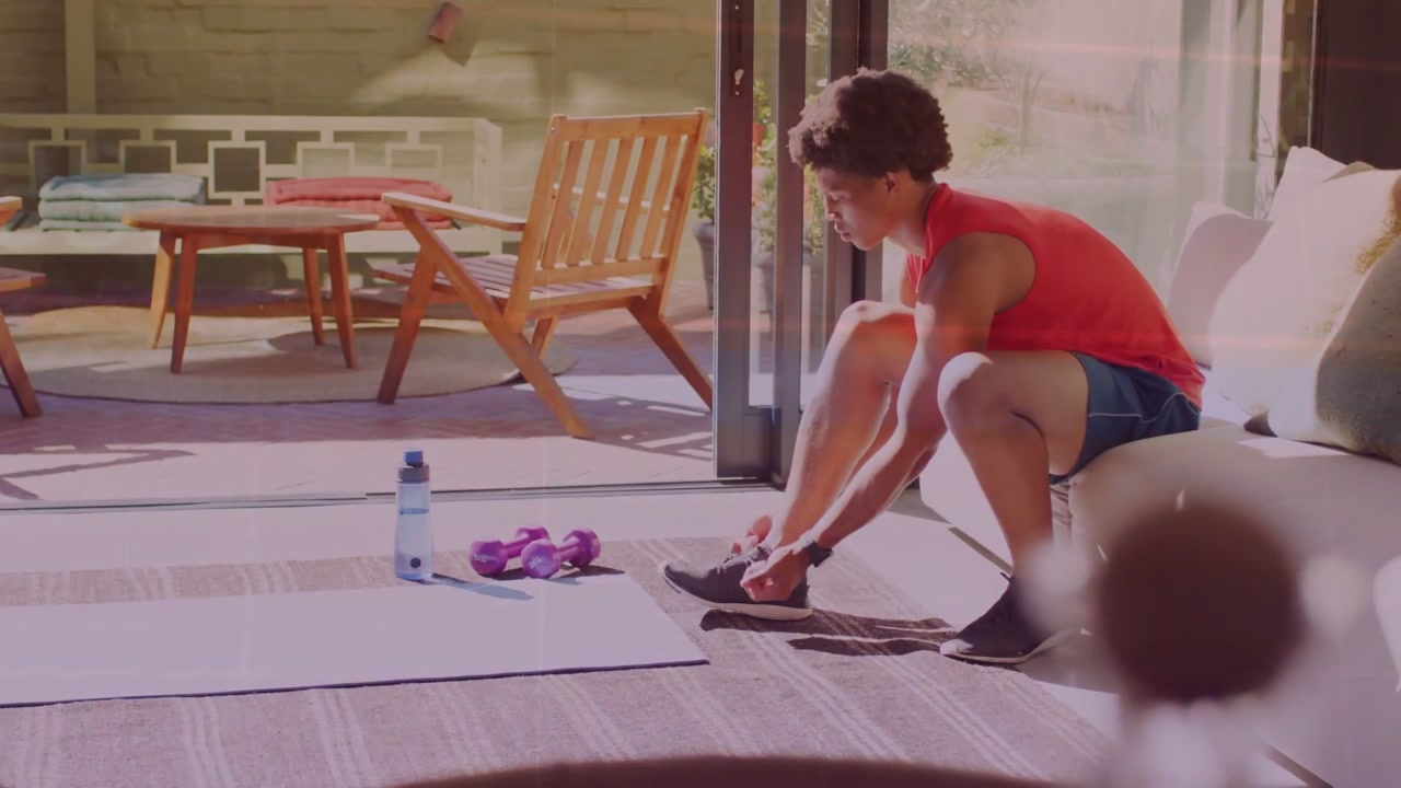 Vertical video: Man preparing for fitness sitting adjusting sneaker as overlay fading revealing mat