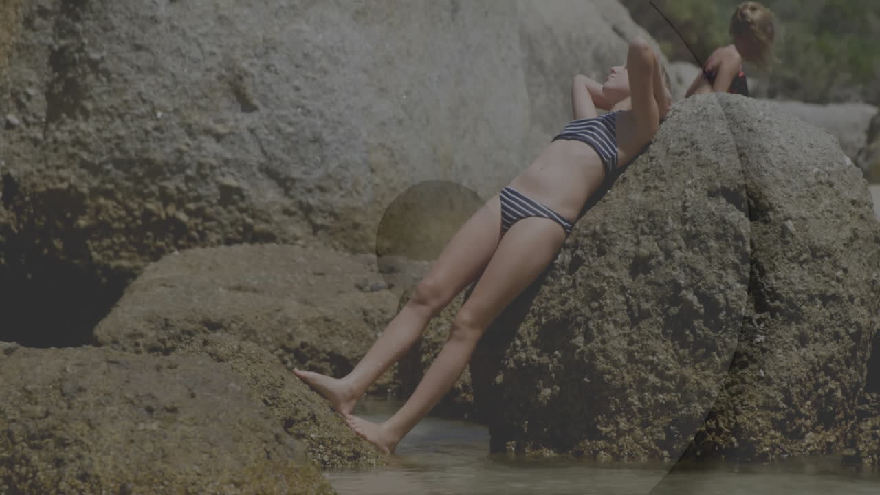 Relaxing by rocky shoreline, person in striped swimsuit near water