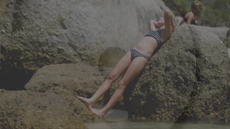 relaxing by rocky shoreline, person in striped swimsuit near water