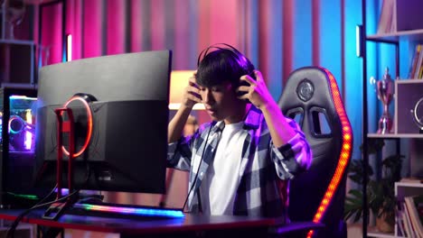 asian teen boy gamer wearing head phones and start play video game on computer