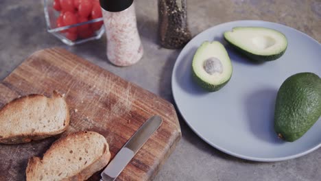 Close-up-of-sliced-bread,-avocado-and-spices-in-kitchen,-slow-motion