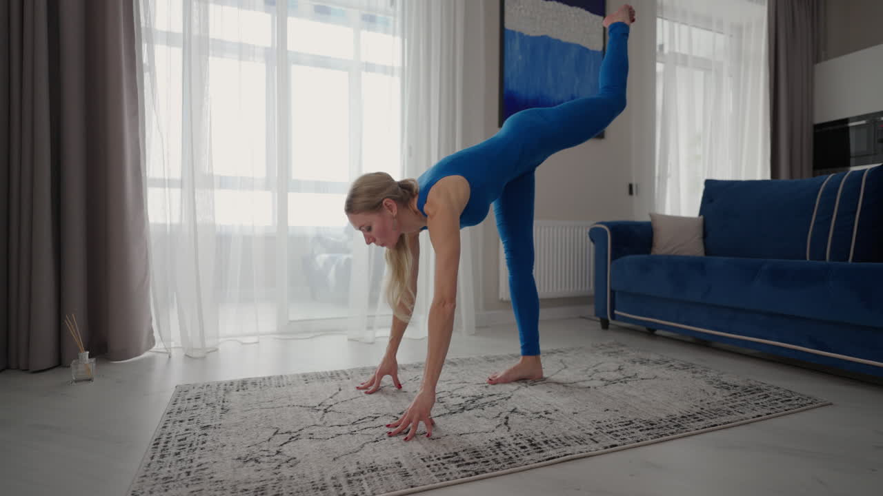 una mujer joven está practicando yoga en casa relajándose en una posición corporal simple sentada en el suelo con hermosos muebles a su alrededor. una mujer delgada con ropa deportiva de pie de rodillas inclinada hacia atrás y haciendo una postura de camello