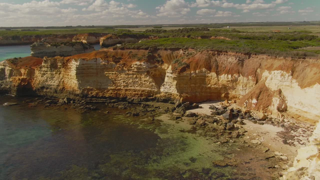 playa rocosa aérea de 4k en el océano azul rodeada de acantilados