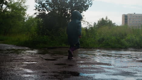 una niña salta felizmente en un charco durante una tormenta.