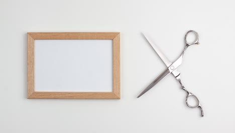 stop motion animation mockup wooden frame flat lay of professional hair cutting shear of the right site of the image template with copy space on white background. hairdresser salon equipment concept