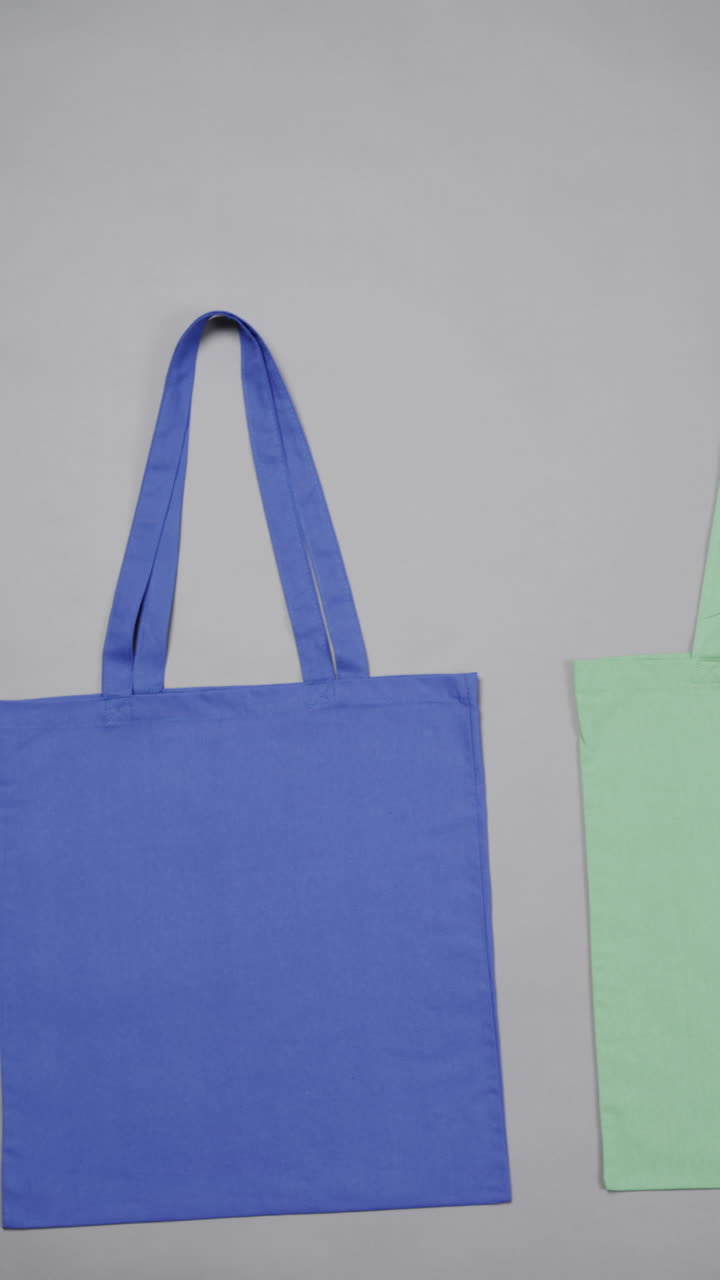 Vertical video of high angle view of blue and green canvas bag with copy space on white background