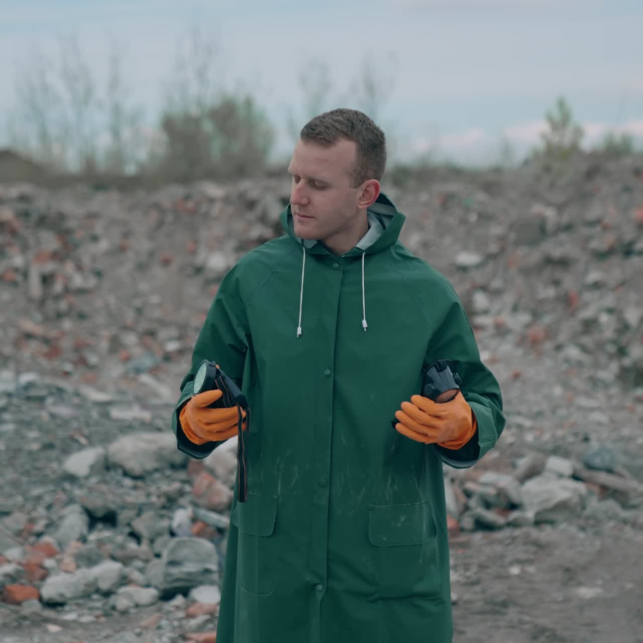 Virologist man taking off his protective costume and respirator gas mask while standing near landfill site pollution and looking at the scale of the disaster